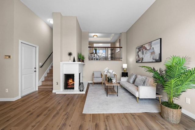 living room with a fireplace, stairway, baseboards, and wood finished floors