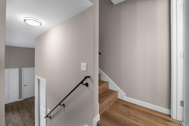 staircase with baseboards and wood finished floors