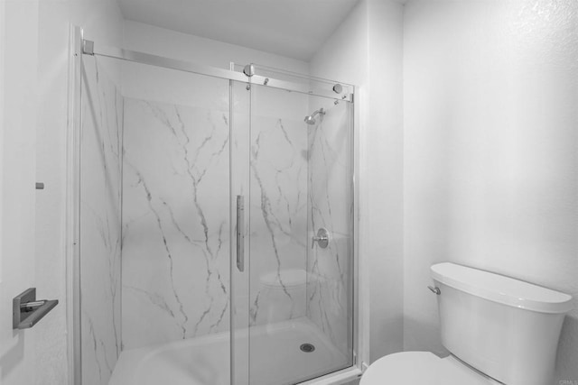 full bathroom featuring toilet and a marble finish shower