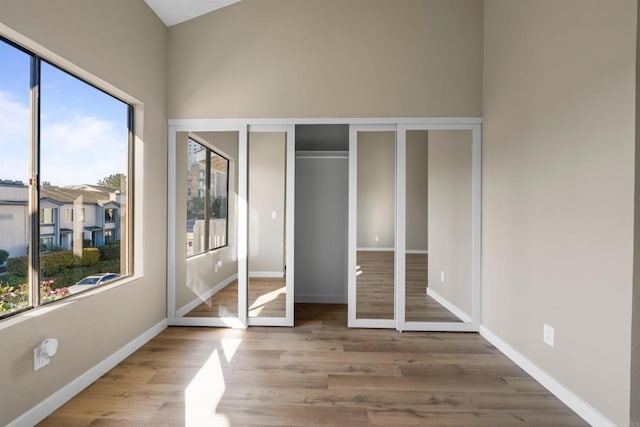 unfurnished bedroom with a towering ceiling, baseboards, and wood finished floors