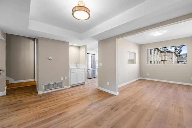 interior space with light wood-type flooring, stairway, baseboards, and visible vents