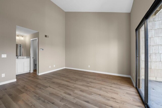 unfurnished room with a sink, visible vents, baseboards, and wood finished floors