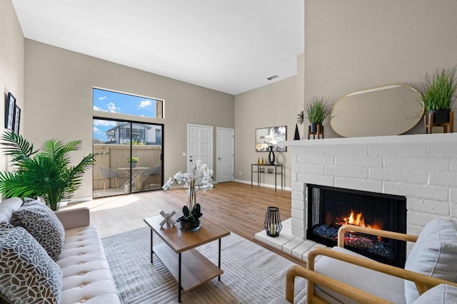 living area featuring a fireplace, wood finished floors, visible vents, and baseboards