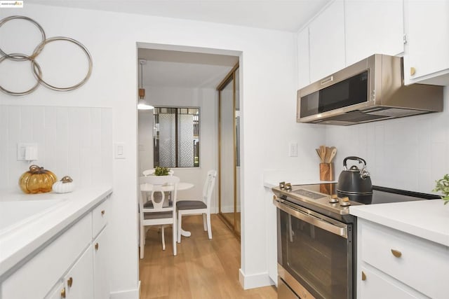 kitchen with light hardwood / wood-style floors, white cabinetry, and appliances with stainless steel finishes