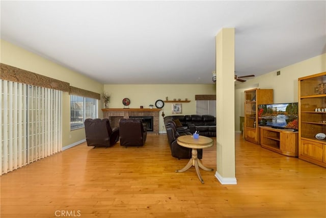 living room featuring a fireplace, light hardwood / wood-style floors, and ceiling fan