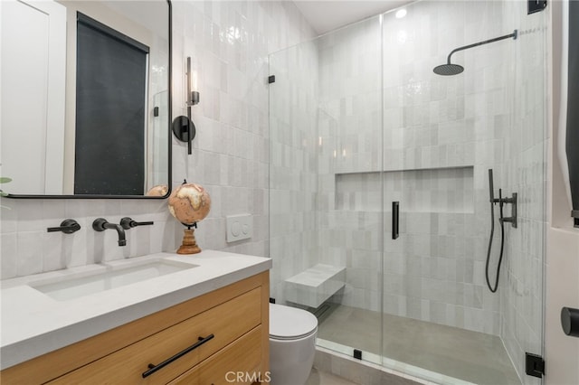 bathroom featuring vanity, backsplash, a shower with door, and toilet