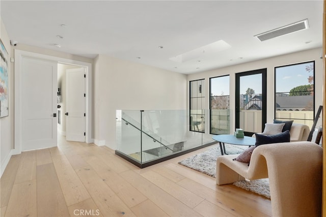 living room featuring a skylight and light hardwood / wood-style flooring