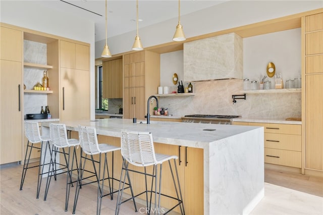 kitchen with decorative light fixtures, premium range hood, a spacious island, and light brown cabinets