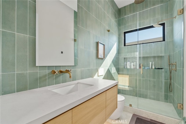 bathroom featuring tile patterned floors, toilet, tile walls, vanity, and a shower with door