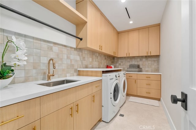 washroom featuring cabinets, washing machine and clothes dryer, and sink