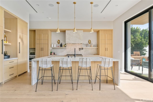 kitchen featuring tasteful backsplash, a large island, pendant lighting, and light brown cabinets