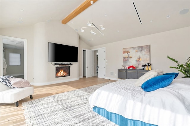 bedroom featuring connected bathroom, lofted ceiling with beams, and light hardwood / wood-style floors