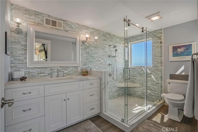 bathroom with vanity, a stall shower, wood finished floors, and visible vents