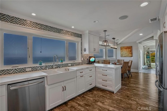 kitchen featuring a peninsula, lofted ceiling, white cabinetry, a sink, and stainless steel appliances