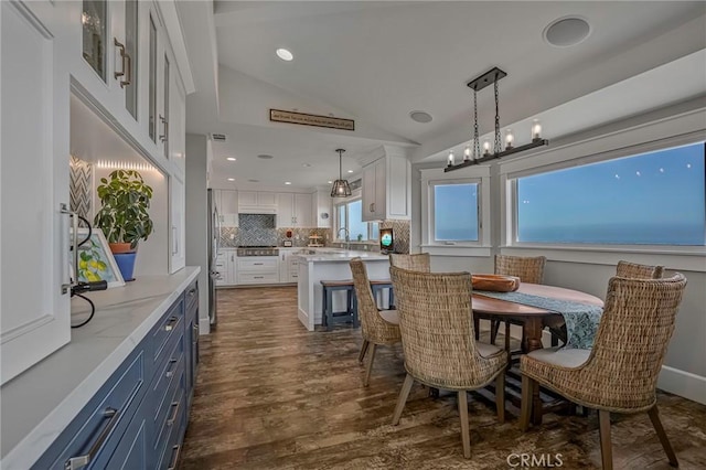 dining room with sink, dark wood-type flooring, and vaulted ceiling