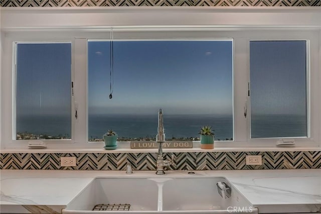interior details with light stone counters, a sink, and tasteful backsplash