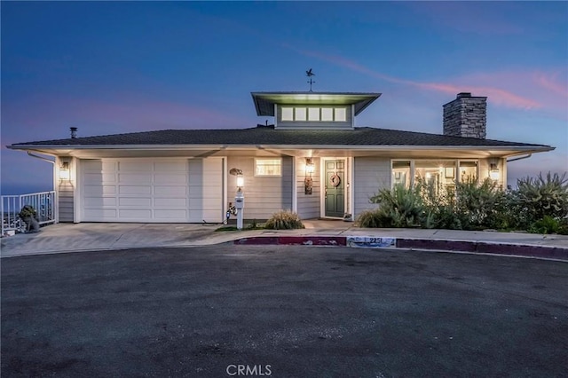 view of front of property with a garage, driveway, and a chimney