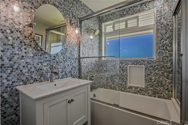 bathroom with vanity, combined bath / shower with glass door, and tile walls