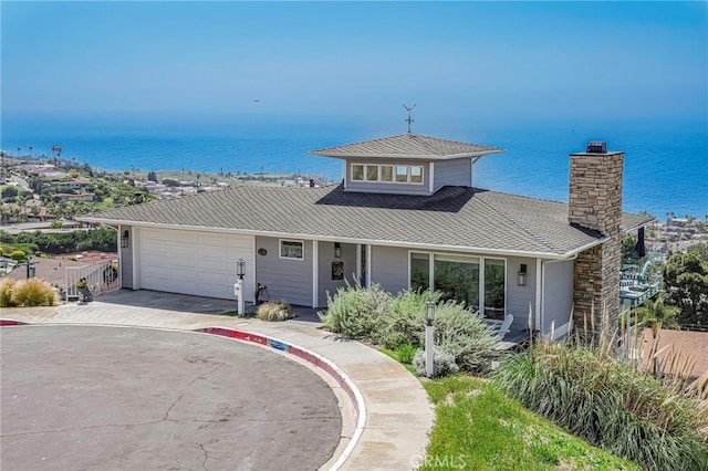 view of front of house with a garage, driveway, a water view, and fence