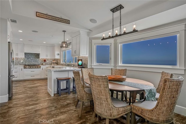 dining room featuring lofted ceiling, dark wood finished floors, a chandelier, and visible vents