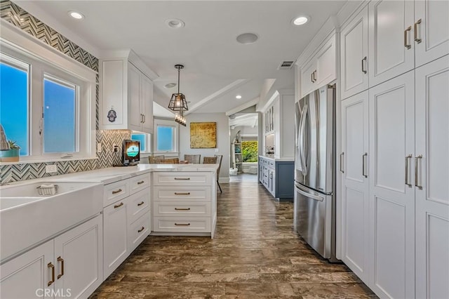 kitchen with visible vents, hanging light fixtures, vaulted ceiling, white cabinets, and freestanding refrigerator