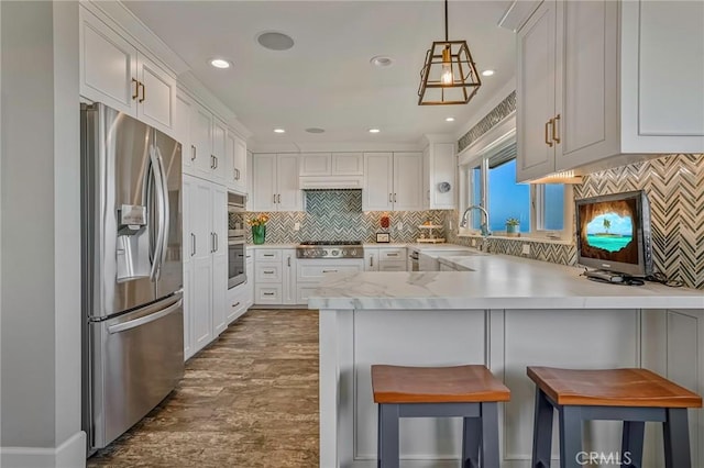 kitchen featuring pendant lighting, stainless steel appliances, a kitchen breakfast bar, and sink