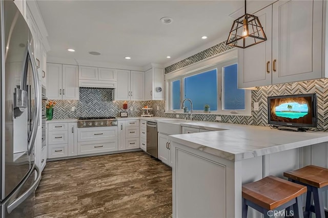 kitchen with stainless steel appliances, a kitchen breakfast bar, kitchen peninsula, and white cabinets