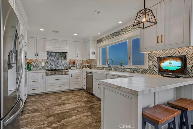 kitchen featuring white cabinets, stainless steel appliances, a sink, and a peninsula