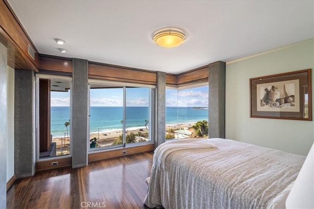 bedroom featuring a water view, a beach view, and dark wood-type flooring