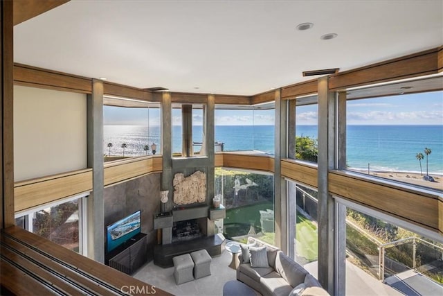 sunroom featuring a beach view and a water view