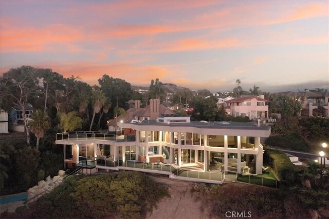 back house at dusk featuring a balcony