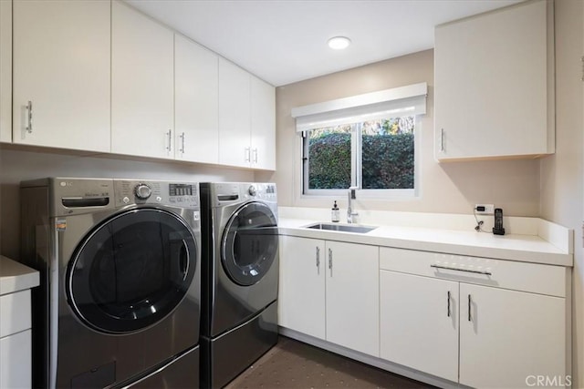 laundry room with sink, washing machine and clothes dryer, and cabinets