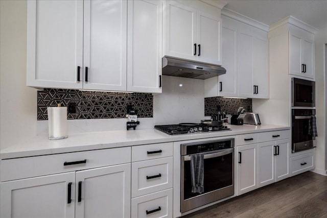 kitchen with white cabinets, stainless steel appliances, dark hardwood / wood-style floors, and tasteful backsplash