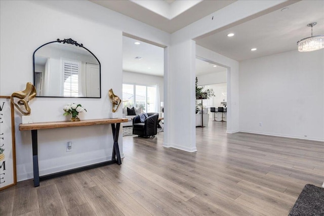 corridor with light hardwood / wood-style floors and a notable chandelier