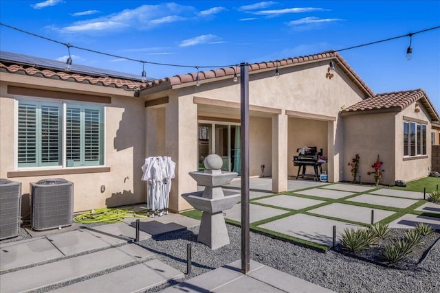 rear view of property with a patio area, solar panels, and central AC