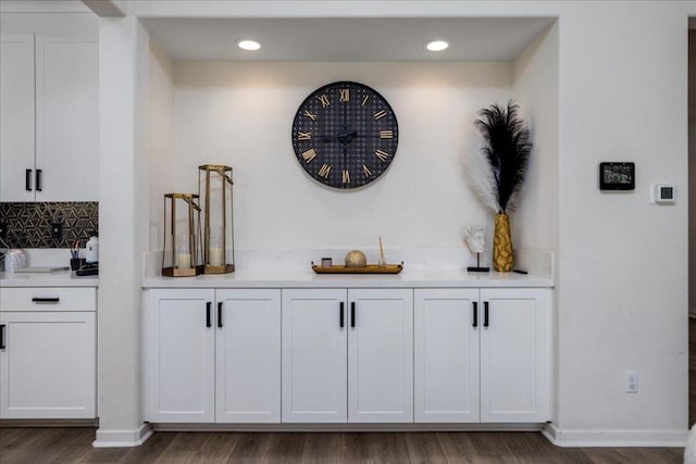 bar featuring dark wood-type flooring, white cabinetry, and decorative backsplash