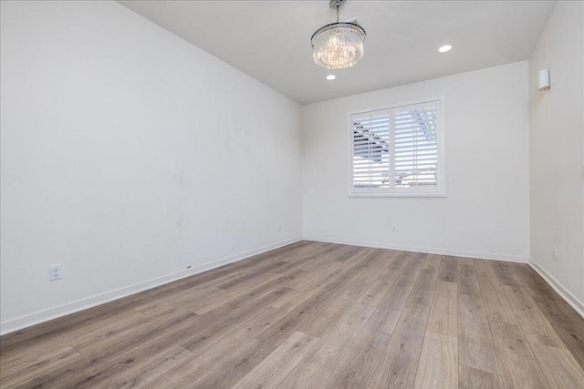 unfurnished room featuring light hardwood / wood-style floors and an inviting chandelier