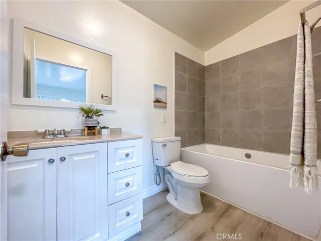 full bathroom with vanity, hardwood / wood-style flooring, tiled shower / bath combo, and toilet