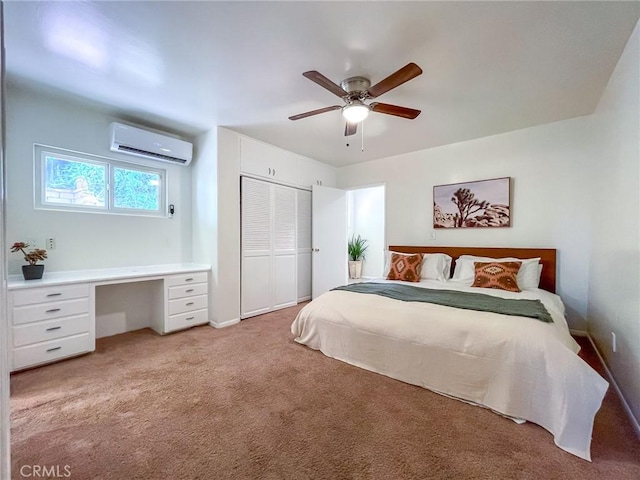 bedroom with built in desk, a closet, ceiling fan, light colored carpet, and a wall mounted air conditioner