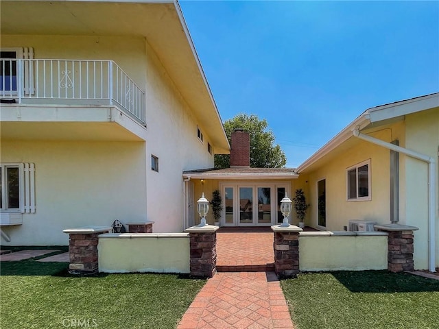 back of property featuring a balcony, a patio, a yard, and french doors