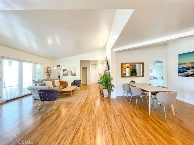 living room featuring lofted ceiling, a wall mounted AC, and light wood-type flooring