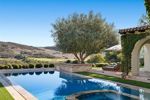 view of pool with a mountain view, a patio area, and an in ground hot tub