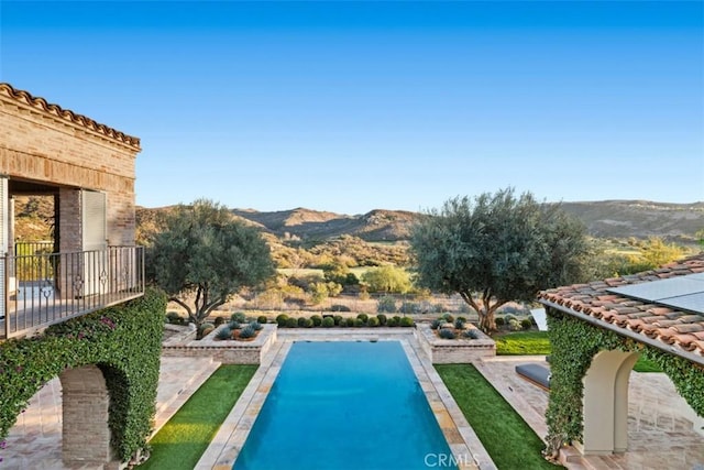 view of swimming pool with a mountain view and a patio area