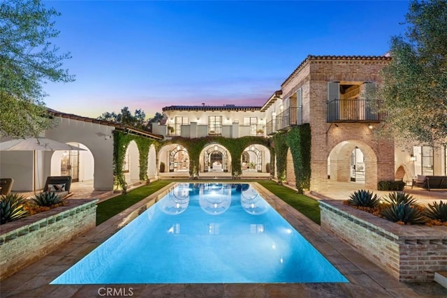 pool at dusk featuring a patio area