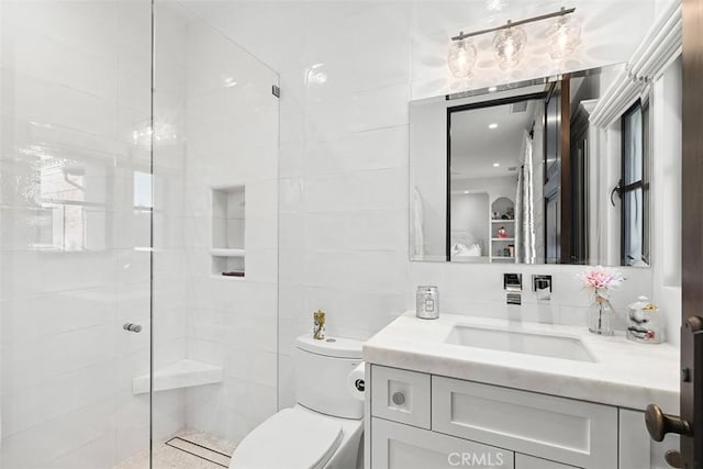 bathroom with vanity, tiled shower, and toilet