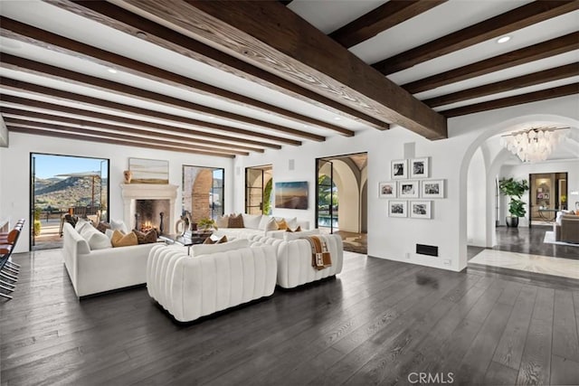 living room with an inviting chandelier, beam ceiling, and dark hardwood / wood-style flooring