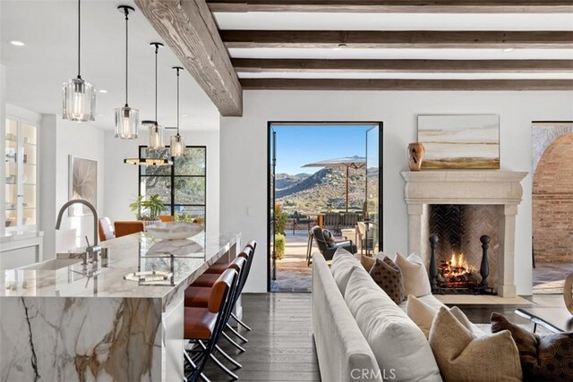 living room featuring hardwood / wood-style floors, beamed ceiling, sink, a high end fireplace, and a mountain view