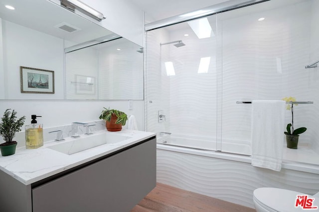 full bathroom with hardwood / wood-style floors, toilet, shower / bath combination with glass door, and vanity