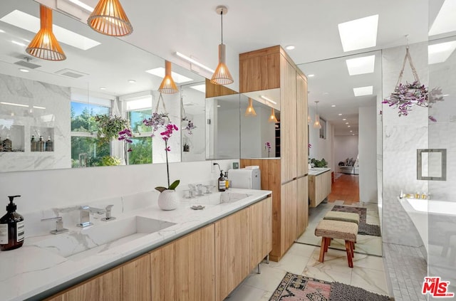 bathroom featuring a tub to relax in, a skylight, and vanity