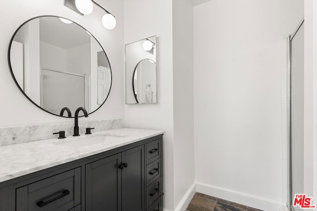 bathroom with a shower with shower door and vanity